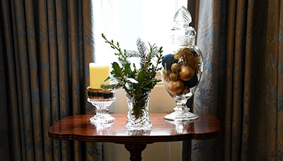 photo - A side table in a Parlor window shines with gold and greens and glass decor.
