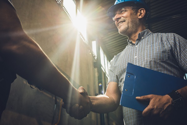 Man in work hat shaking hands with other man