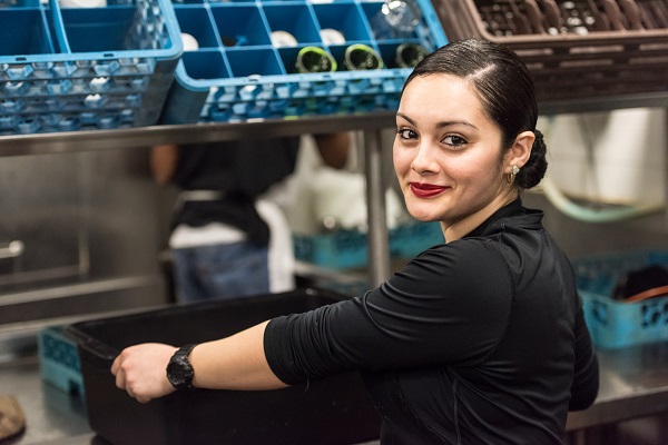 Woman moving glass rack in kitchen of restaurant